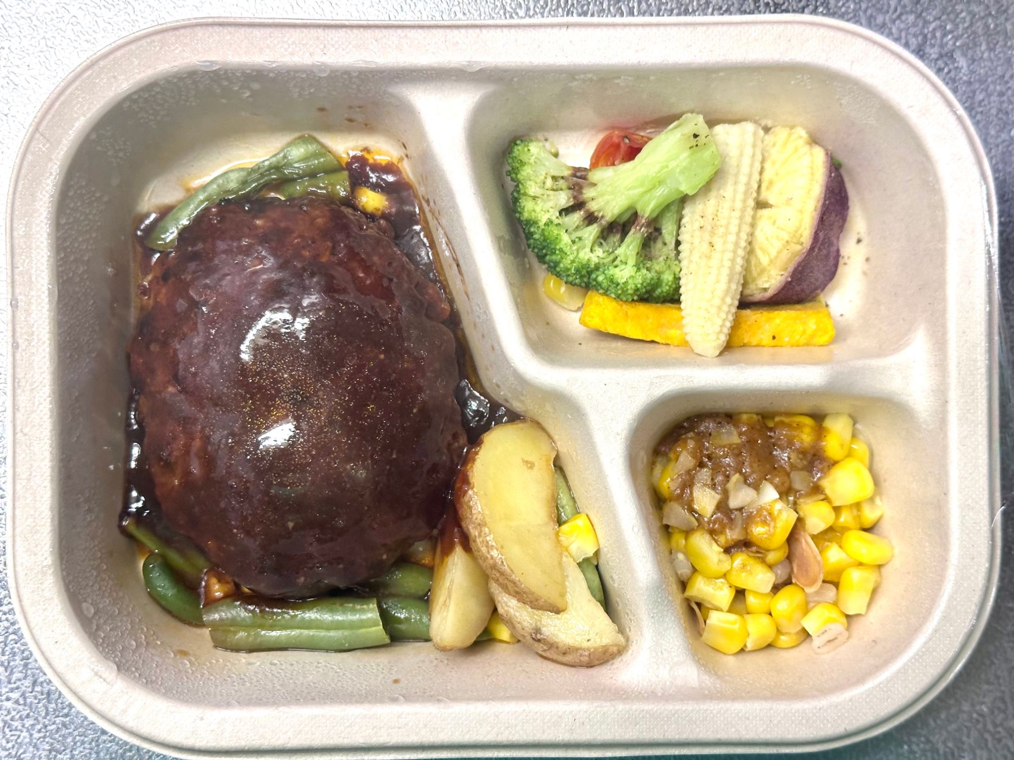 グリーンスプーンDELI BENTO 特製デミグラスハンバーグをレンチンした状態。3室トレーにハンバーグ・温野菜サラダ・雑穀とコーンのカレー